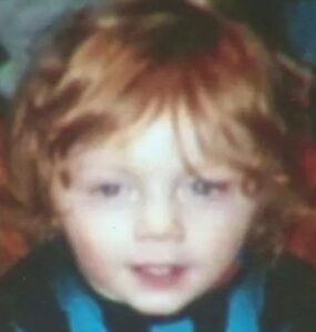 Photo of a pale-skinned, blue-eyed toddler with shaggy red hair.