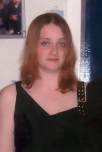 Photo of Sonya Todd, a young woman with shoulder length light-brown hair, wearing a black sleeveless dress. She has pale skin and blue eyes.