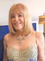 Photo of Maureen Boyce, a middle-aged woman with fair skin and straight blonde chin-length hair. She is wearing a fancy sequined dress and silver necklace.