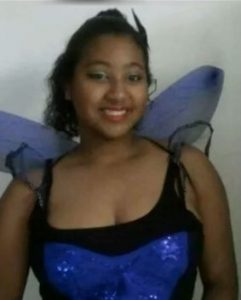 Photo of Charity Depina, a young woman with curly black hair and tan skin, wearing a blue fairy costume with wings showing behind her back.