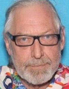 Photo of Ronald Bettig, an elderly man with pale skin and white hair and beard, wearing glasses and a colorful shirt.