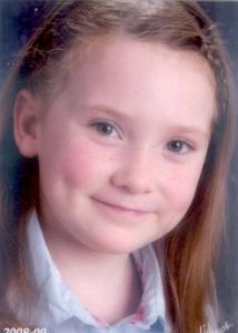 Photo of Camden Fry, a young girl with light-brown hair, blue eyes, and pale skin. Her hair is held back in a hair band and she is smiling for the camera, revealing dimples in her cheeks.