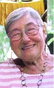 Photo of an older lady wearing a striped sweater and glasses; her gray hair is cut short.