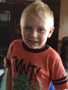 Photo of Joe Daniels, a little blond boy with fair skin and pink cheeks, wearing an orange Ninja Turtles T-shirt and smiling for the camera.