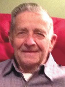 Photo of Leo McWilliams, an older man with gray hair and fair skin, wearing a plum-colored shirt and smiling for the camera.