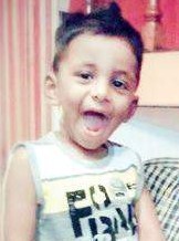 Photo of Samvith, a small boy with olive-toned skin and dark-brown hair, wearing a printed tank top. He has his mouth open and is looking at the camera happily.