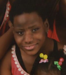 Photo of Jada Wright, a girl with short black hair and brown skin. She is wearing a coral-colored dress.