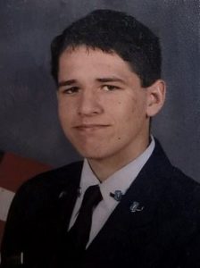 Portrait photo of Austin Steele, a young man with brown hair and fair skin, wearing a black suit and tie.