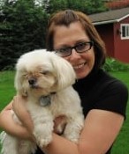 Photo: Woman with a pageboy haircut and glasses hugging a fluffy white dog.