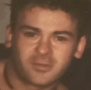 Blurry photo of a young man with tanned skin and dark brown hair.