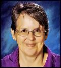 Portrait photo of a middle-aged white woman with short dark hair, wearing glasses.