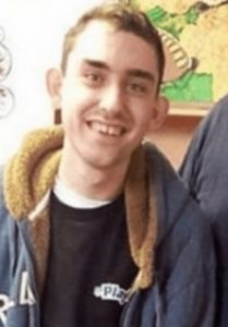 Photo of Joel Parks, a young man with short dark hair and pale skin, smiling for the camera, wearing a navy blue jacket.