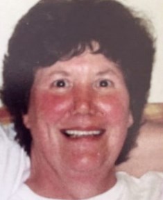 Photo of a middle-aged woman with brown eyes, red cheeks and short curly brown hair.