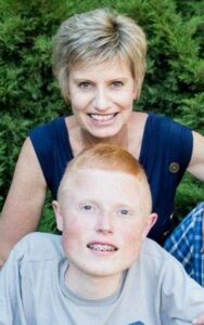 Photo of a redheaded teenage boy and a smiling older blonde woman.