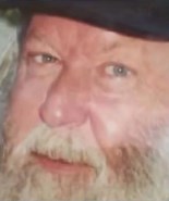 Close-up photo of an older man with fair skin and a white beard and mustache.