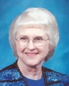 Photo: A white-haired, fair-skinned older lady wearing glasses and a turquoise sweater.