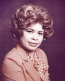 Sepia portrait photo of a middle-aged African-American woman with a perm, wearing a suit jacket and scarf.