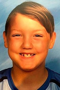 Photo of a boy with straight dark-blond hair, smiling for the camera.