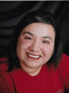 Portrait photo of a young woman with short dark hair, wearing a red dress and make-up.