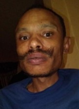 Photo of African-American man with a neat mustache, wearing a blue top.
