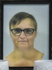Photo of a middle-aged woman with wispy, short brown hair, pale skin, and glasses.