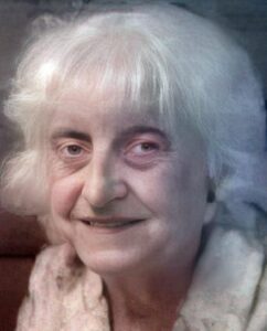 Photo of an elderly woman with wispy white chin-length hair and pale skin.
