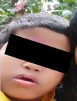 Photo of a young boy with a censor bar across his eyes. He has short black hair and tan skin.