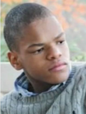Photo of a young man with very short black hair and mid-brown skin, wearing a gray sweater.