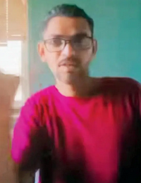 Photo of a man with tan skin and short black hair, wearing glasses and a red T-shirt.