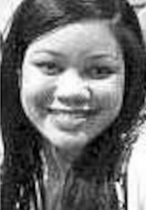 Black and white photo of a young woman with straight dark hair and light skin, smiling for the camera. She has Asian eyes and a broad nose; her teeth are white and straight.