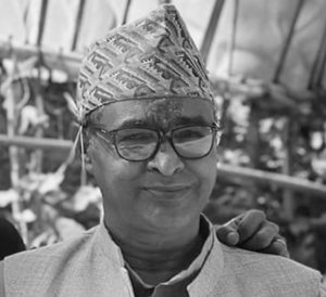 black and white photo of an older southeast asian man wearing glasses and traditional headwear