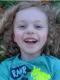 Photo of smiling child with fair skin and long, curly blond hair, wearing a teal T-shirt printed with the word, "Rawr". 