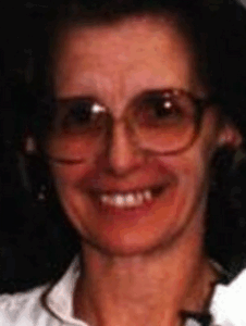 Photo of a woman with light skin and dark hair; she is wearing tinted glasses with large frames.