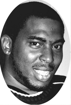 Black and white photo of an African-american man with a chinstrap and mustache, his hair cut short. He is smiling for the camera.